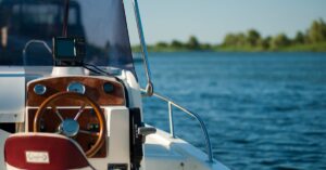 A yacht steering wheel with a serene water view during a bright summer day offering leisure and adventure.