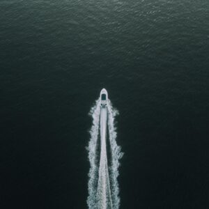 A high-angle shot of a boat creating ripples as it speeds across the tranquil sea, highlighting a peaceful maritime adventure.