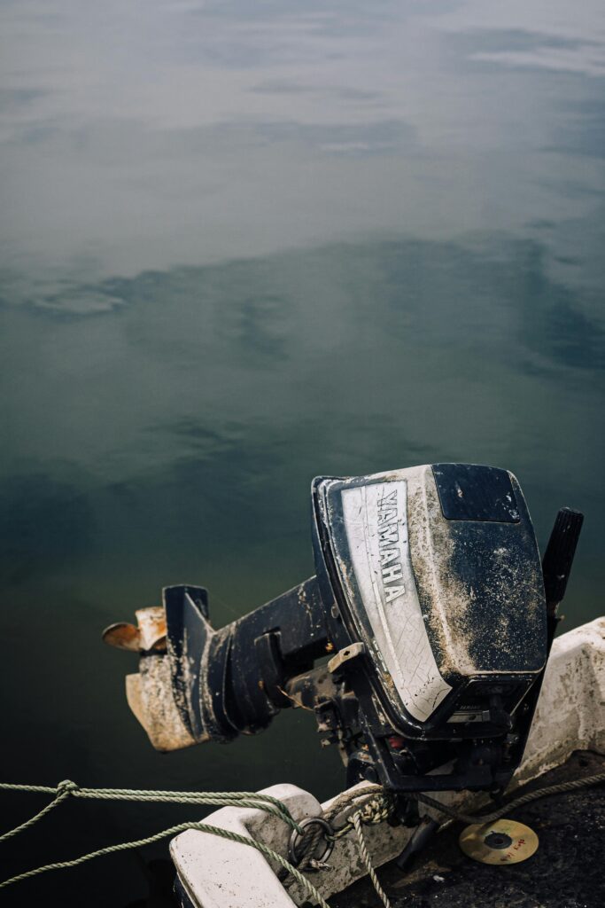 Detailed view of a Yamaha boat motor attached to a vessel over calm water.